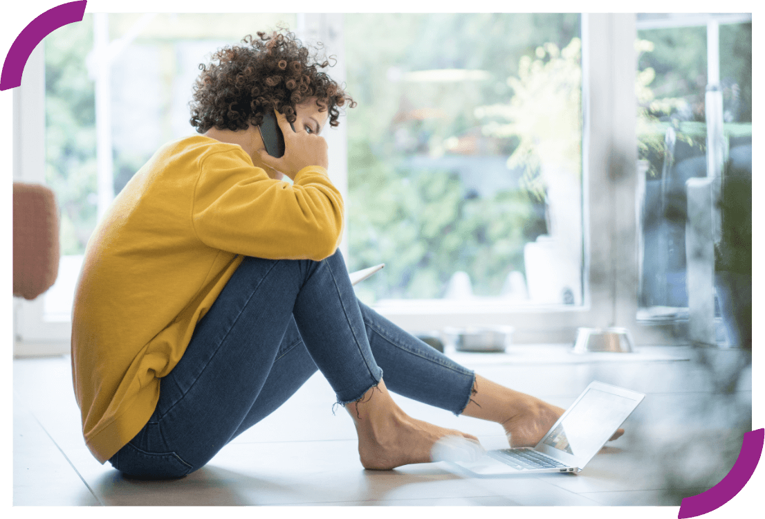 Woman on the phone while looking at her laptop.